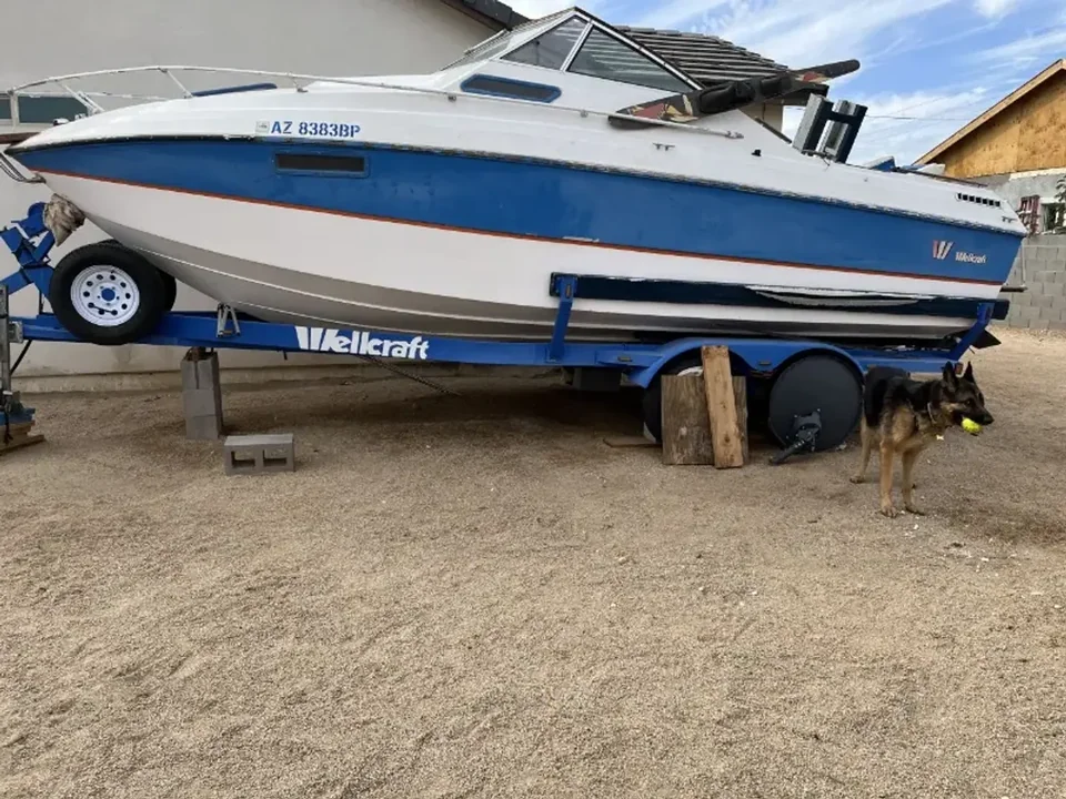 Blue and white powerboat resting on blocks above a trailer