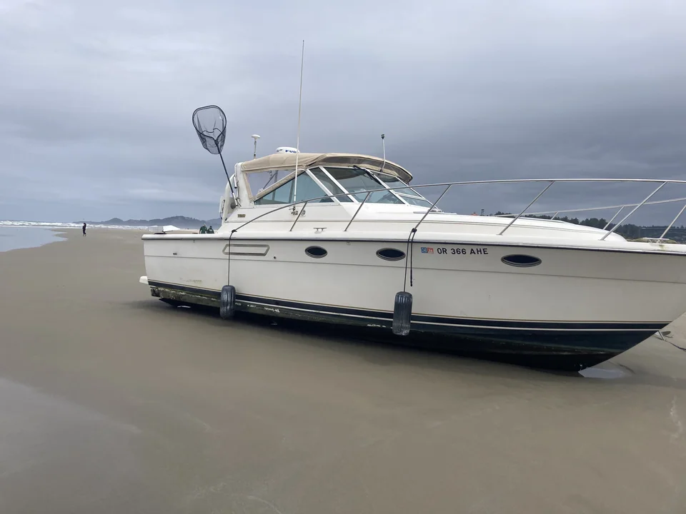 Cabin cruiser stranded on sand near the waterline