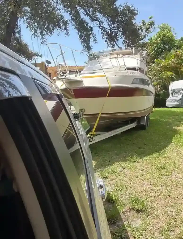 Covered motorboat on a trailer beside a vehicle