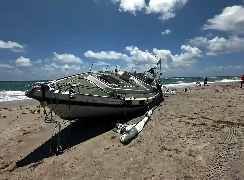 Damaged motorboat hull resting on a sandy beach