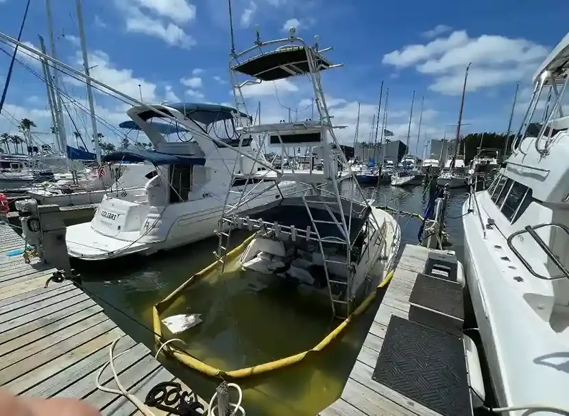 Low-sitting cabin boat surrounded by marina docks and other vessels