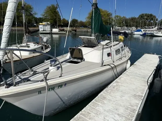 Narrow white sailboat tied alongside a floating walkway