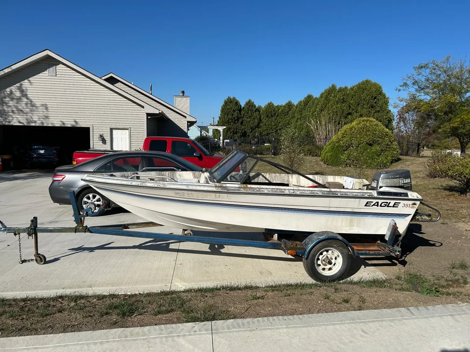 Open motorboat on a single-axle trailer across a driveway