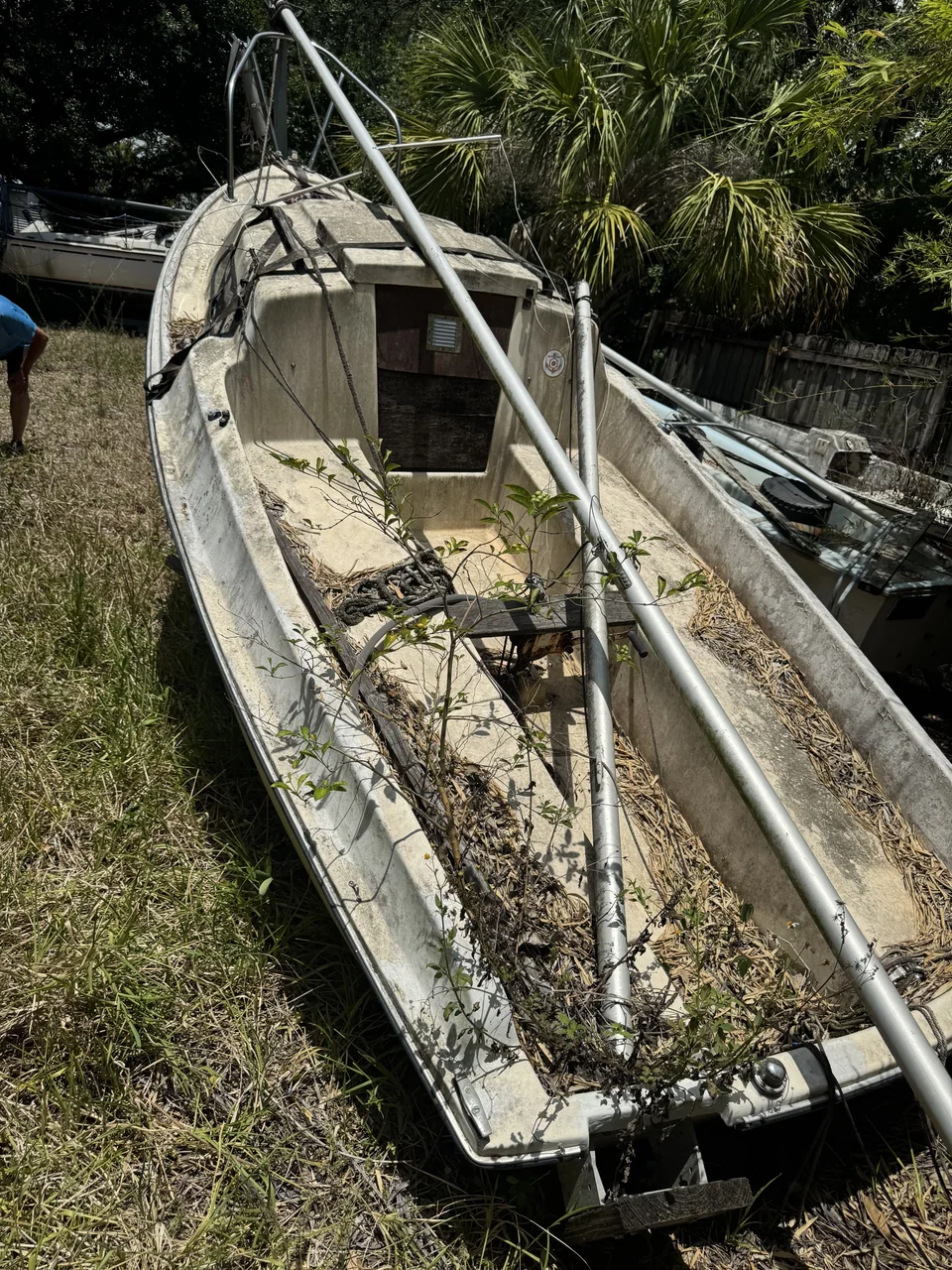 Open view into a stripped boat interior filled with leaves and debris