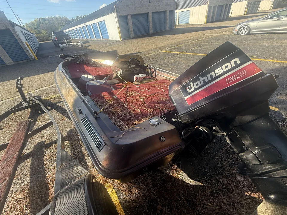 Red open motorboat with a dark outboard engine in a storage yard