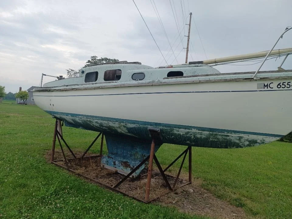 Sailboat with a weathered blue keel supported on yard stands