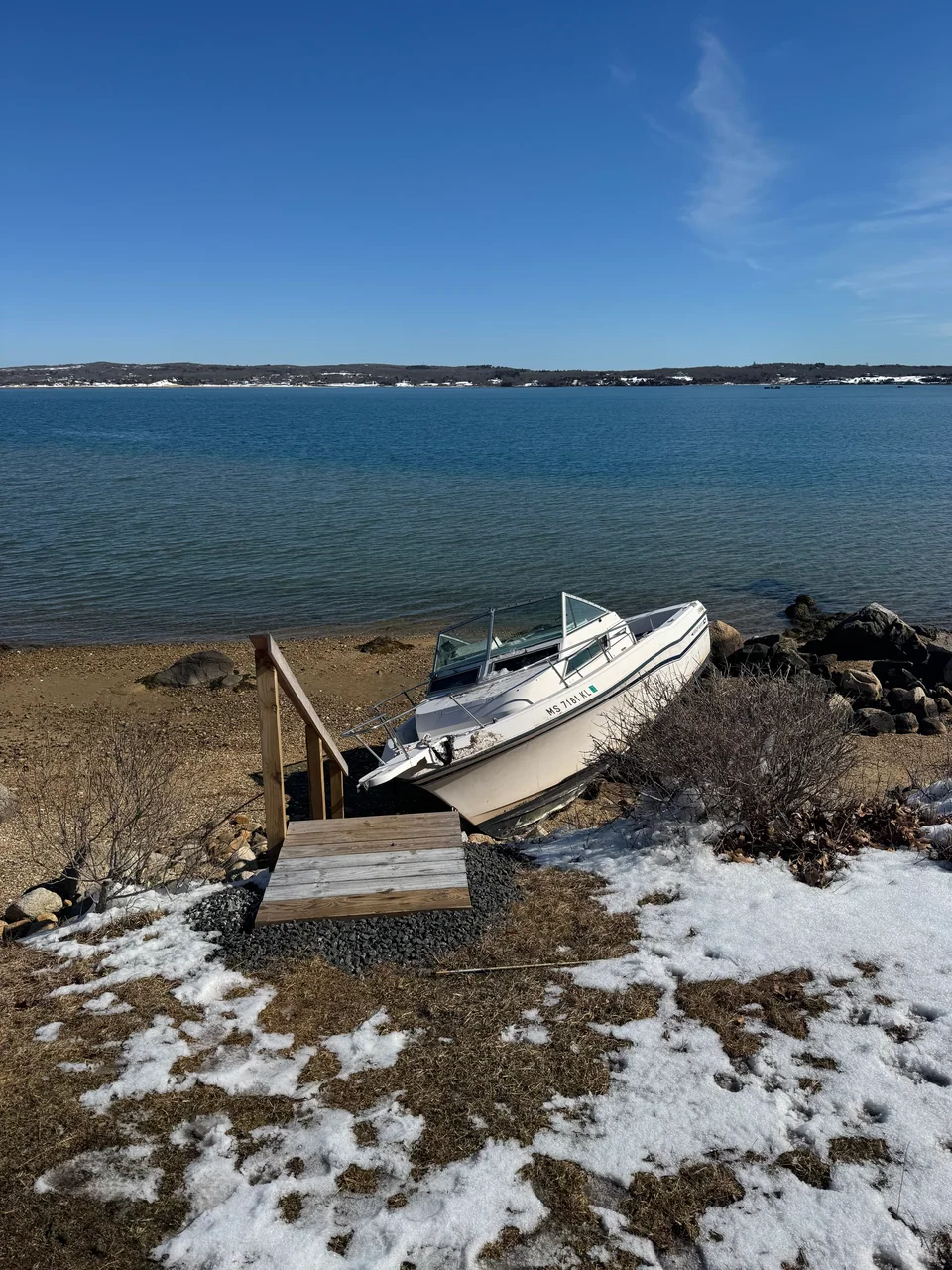 Small white boat resting on a wintry shoreline