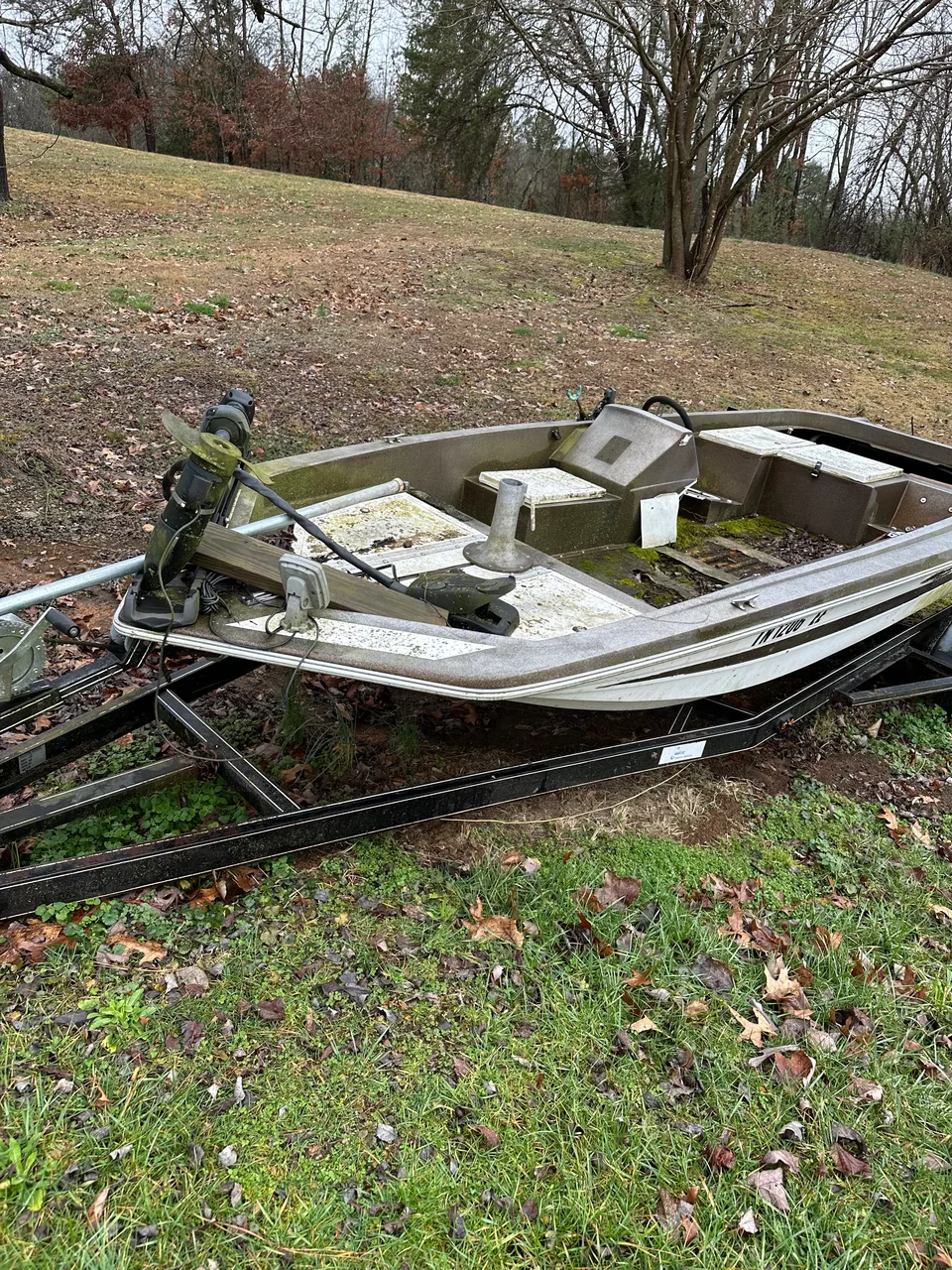 Stripped open hull and trailer resting on a grassy slope