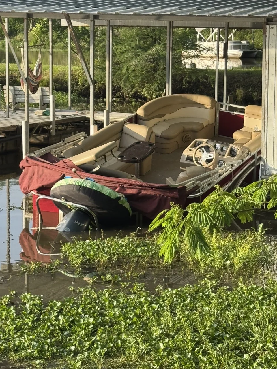 Weathered red and white motorboat stored beneath an open shelter