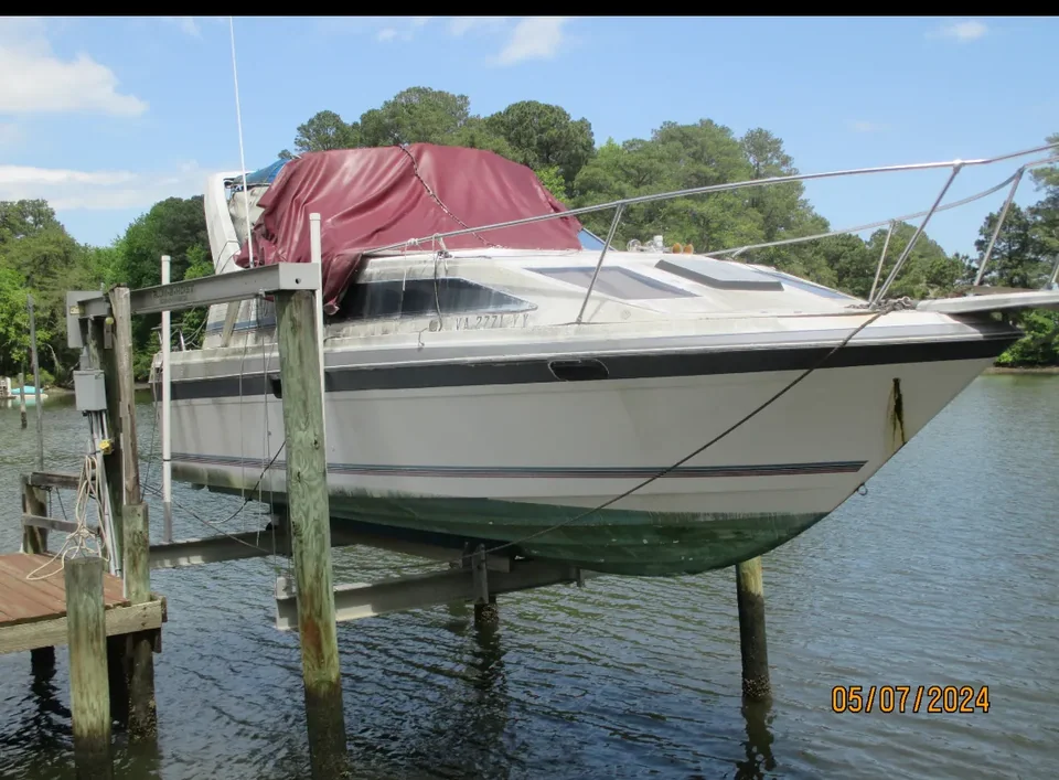 White motorboat with a red cover raised on a dockside lift
