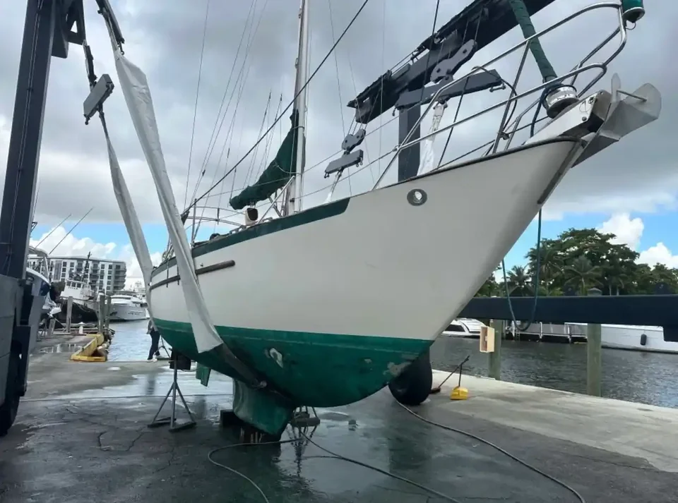White sailboat with a green keel hanging in lifting straps