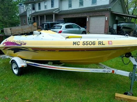 Yellow open motorboat on a trailer in front of a building